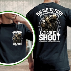 Könnte beinhalten: Schwarzes T-Shirt mit einer Grafik eines Sensenmanns, der zwei Pistolen hält. Auf der Vorderseite des Shirts steht "Boomer" und "Est. 1960". Auf der Rückseite steht "Too Old To Fight, But I Can Still Shoot, Pretty Darn Good".