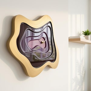 Può includere: Un orologio da parete con una cornice in legno chiaro dalla forma organica irregolare e un quadrante viola intenso, stratificato, in stile topografico. Il centro presenta sottili lancette color oro. Il design crea profondità con ritagli ondulati.