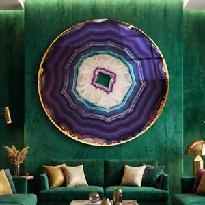 Könnte beinhalten: Ein luxuriöses Wohnzimmer mit smaragdgrünen Samtsofas, goldenen Akzenten und einem großen, runden Wandkunstwerk, das einer Geode ähnelt. Der Raum verfügt über einen gemusterten Teppich, einen Marmor-Couchtisch und goldene Stehlampen.