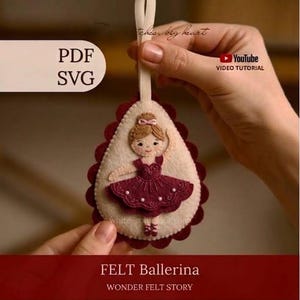 May include: A teardrop-shaped felt ornament featuring an embroidered ballerina in a dark red tutu. The ornament has a scalloped dark red border, a cream-coloured centre, and a hanging loop. Text includes PDF, SVG, YouTube VIDEO TUTORIAL, and FELT Ballerina.