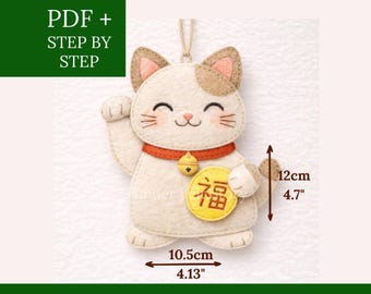 May include: A felt cat ornament with a red collar and a gold bell. The cat has brown ears and a gold emblem with the Chinese character for "fortune". The ornament is 4.7 inches tall and 4.13 inches wide. Text on the image says "PDF + STEP BY STEP" and "FELT DESIGN".