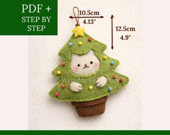 Può includere: Un ornamento per albero di Natale in feltro verde con una faccia di gatto, largo 10,5 cm e alto 12,5 cm. L'ornamento ha accenti di perline colorate e una base di vaso marrone. Il testo sull'immagine recita "FELT DESIGN" e "WONDER FELT STORY".