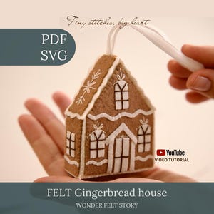 Op de afbeelding: Een peperkoekhuisje-ornament van bruin vilt met witte geborduurde details, waaronder ramen en dakranden. De tekst luidt Tiny stitches, big heart, PDF, SVG, YouTube VIDEO TUTORIAL en FELT Gingerbread house WONDER FELT STORY.