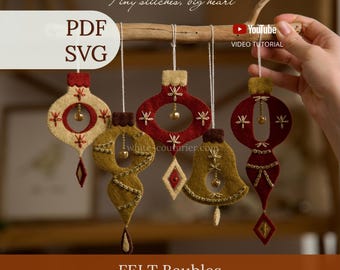 Può includere: Cinque ornamenti in feltro rosso, crema e verde oliva appesi a un ramo di legno. Gli ornamenti presentano dettagli ricamati, piccoli campanelli metallici e forme geometriche. Il testo include "Tiny stitches, big heart", "PDF SVG", "YouTube VIDEO TUTORIAL", "white-couturier.com", "FELT Baubles" e "WONDER FELT STORY".