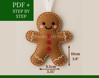 May include: A felt gingerbread man decoration with a white stitched outline, rosy cheeks, and a smiling face. It has red button accents and a white ribbon for hanging. The ornament is 10 cm tall and 8.5 cm wide. The text "PDF + STEP BY STEP" and "FELT DESIGN" are also visible.