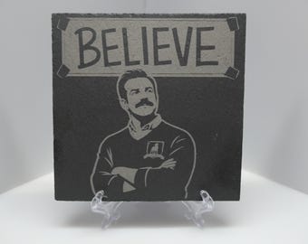 Posavasos de pizarra grabado con láser, inspirado en la canción "Believe" de Ted Lasso.