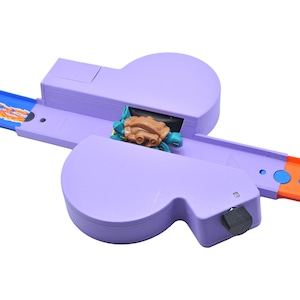 May include: A purple toy race track with a turtle-shaped car. The track has blue and orange sections. The toy is designed for children's play and features a unique design.