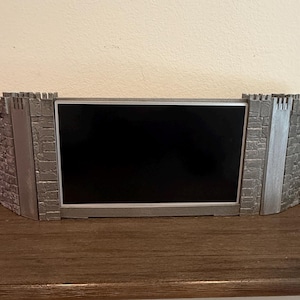 以下が含まれることがあります： 黒いディスプレイを備えた、灰色の要塞スタイルの卓上スクリーン。 スクリーンは、石レンガのデザインと赤い「D&D」ロゴが付いた2つのサイドパネルで挟まれています。 テーブルトップロールプレイングゲーム用に設計されています。