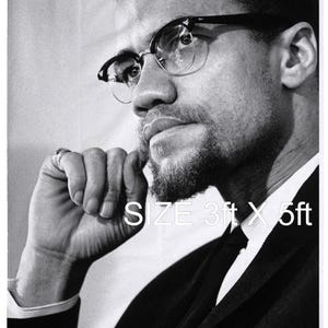 Puede incluir: Bandera con retrato en blanco y negro de Malcolm X, con gafas y un traje. La bandera está etiquetada como "SIZE 3ft X 5ft" e incluye el texto "MALCOLM X El-Hajj-Malik-Shabazz" en la parte inferior. La imagen es un primer plano de su rostro.