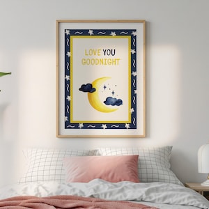 Puede incluir: Una impresión artística enmarcada con un diseño de acuarela. La impresión presenta una luna creciente amarilla, nubes azul oscuro y estrellas. El texto "LOVE YOU GOODNIGHT" se muestra en amarillo. El marco tiene un borde azul marino con estrellas blancas.