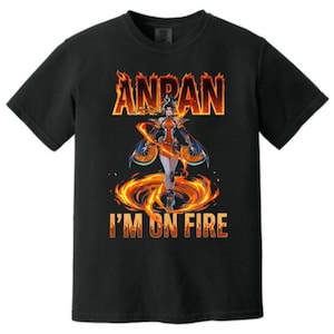 Puede incluir: Una camiseta negra de manga corta con un estampado gráfico de un personaje rodeado de llamas naranjas y amarillas. El texto ANPAN aparece en una fuente de fuego arriba, y el texto I'M ON FIRE aparece en una fuente similar debajo.