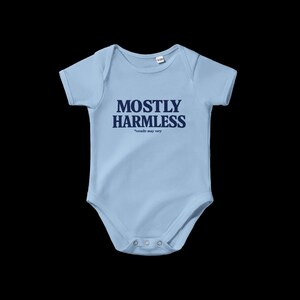 Könnte beinhalten: Hellblaues Baby-Body mit dem marineblauen Schriftzug "MOSTLY HARMLESS" und dem Text "results may vary" darunter. Der Body hat kurze Ärmel und Druckknöpfe am unteren Saum.