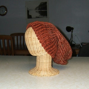 May include: A brown knitted beanie hat on a wicker hat form.