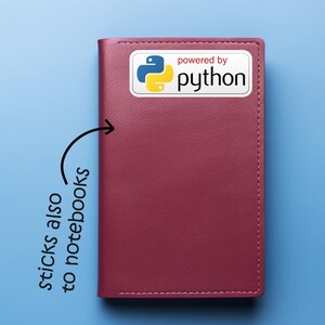 May include: A burgundy notebook with a white sticker that says "powered by python" with the Python logo. The notebook is on a blue background. Text on the image says "sticks also to notebooks".