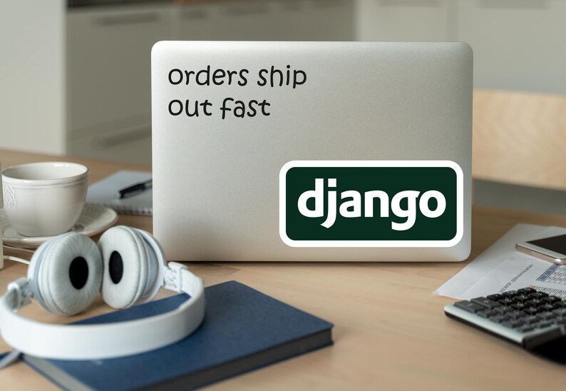 Może przedstawiać: Laptop z naklejką z napisem "orders ship out fast" i naklejką Django. Białe słuchawki, niebieski notatnik, filiżanka i kalkulator leżą na drewnianym biurku.