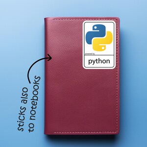 May include: A burgundy notebook with a white sticker featuring the Python programming language logo. The sticker has a blue and yellow snake icon and the word "python" below. The text "sticks also to notebooks" is written on the left.