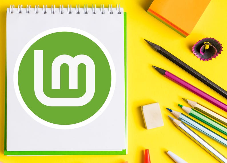 May include: A white spiral-bound notebook with a green border and a green circle logo with the letters "Lm" is on a yellow surface. Pencils, an eraser, and a pencil sharpener are also on the surface.