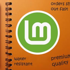 May include: An orange spiral-bound notebook with a black pen resting on the left side. A green circle with a white "lm" logo is centered on the page. Text includes "orders ship out fast", "water resistant", and "premium quality".