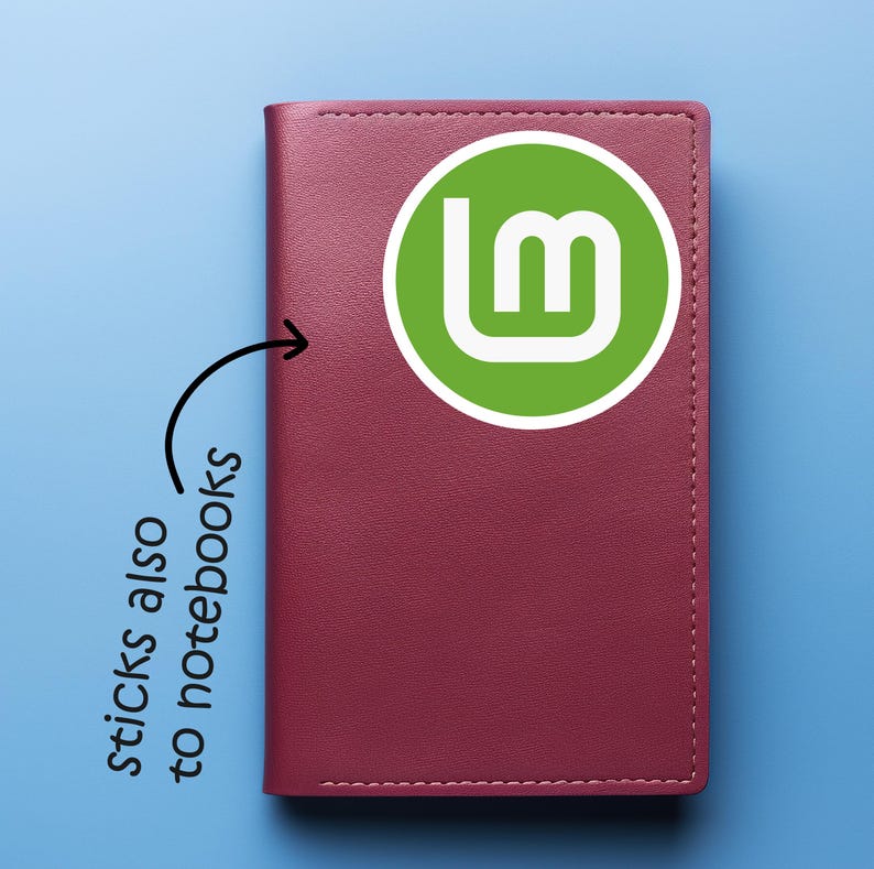 May include: A burgundy notebook with a green and white logo. The notebook has a stitched border and the text "sticks also to notebooks" is written on the side.