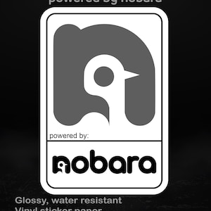 May include: A white-bordered sticker with a gray penguin-like logo and the text "powered by nobara." The sticker also includes the text "Glossy, water resistant Vinyl sticker paper Available in different sizes."