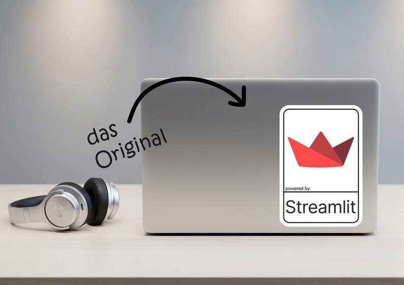 K&ouml;nnte beinhalten: Ein Laptop mit einem Aufkleber mit einem roten Papierboot-Design und dem Text "powered by Streamlit". Die Worte "das Original" sind auf dem Laptop geschrieben. Silberne Kopfh&ouml;rer liegen auf dem Tisch.
