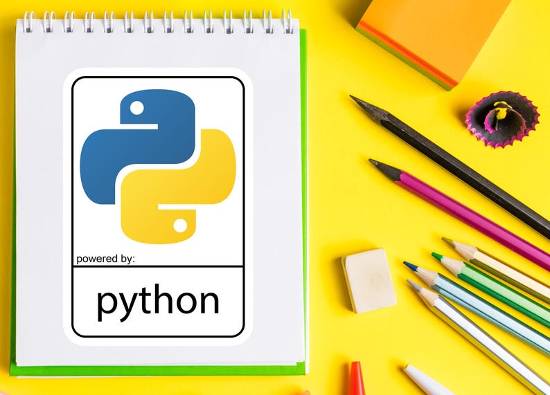 May include: A white spiral-bound notebook with a green border displays a Python logo in blue and yellow, with the word "python" below. Pencils, an eraser, and a pencil sharpener are scattered on a yellow surface.