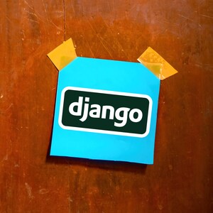 Może przedstawiać: Jasnoniebieska karteczka samoprzylepna z napisem "django" białymi literami w zielonym prostokącie, przyklejona do drewnianej powierzchni dwoma kawałkami ż&oacute;łtej taśmy. Drewniana powierzchnia jest brązowa.