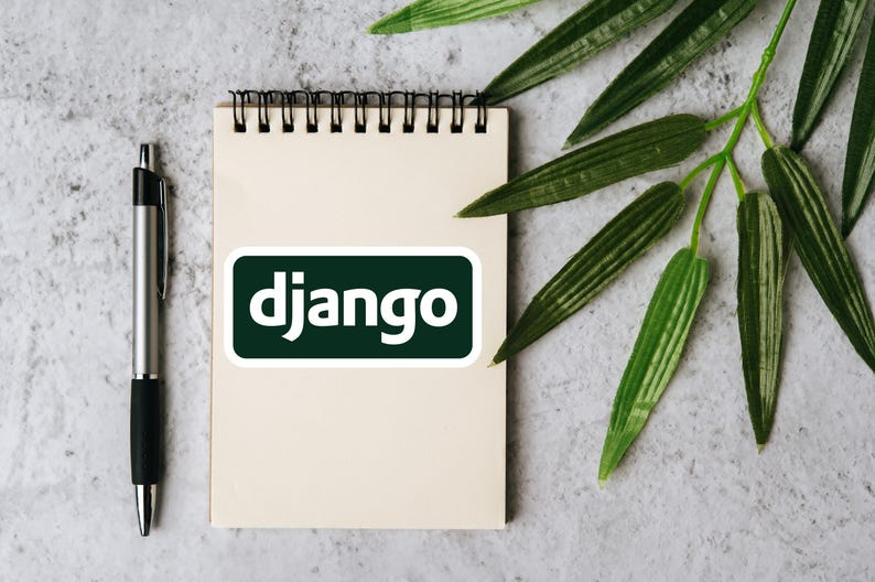 Może przedstawiać: Notatnik ze spiralą, długopis i naklejka z napisem "django" białymi literami na ciemnozielonym tle. Zielone liście w tle. Długopis jest srebrny i czarny.