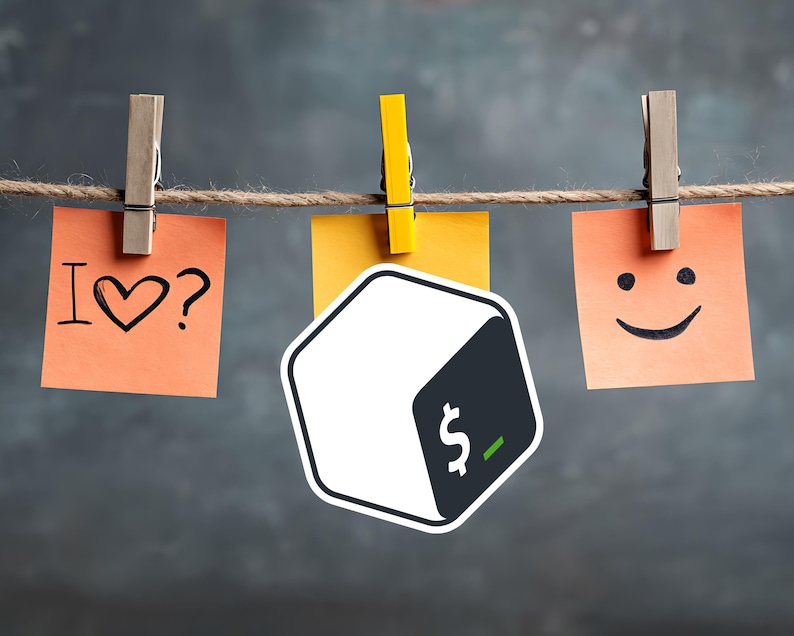 May include: A decorative arrangement featuring three sticky notes suspended by clothespins on a string. The notes display the phrases "I ♡?" and a smiley face, with a cube-shaped logo in the center. The background is a textured gray.