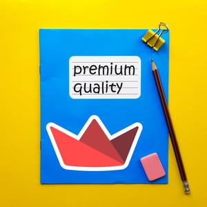 Op de afbeelding: Een blauw notitieboek met de woorden "premium quality" op een witte sticker. Een rode en witte papieren kroonsticker staat onder de tekst. Een potlood, gum en een gele paperclip liggen ook op de gele achtergrond.