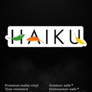 Op de afbeelding: Een zwarte sticker met het woord "HAIKU" in grote, vette, zwarte letters. De "H" heeft een groen blad, de "A" heeft een oranje blad en de "U" heeft een geel blad. De tekst "stick me! somewhere cool..." staat boven het woord "HAIKU".