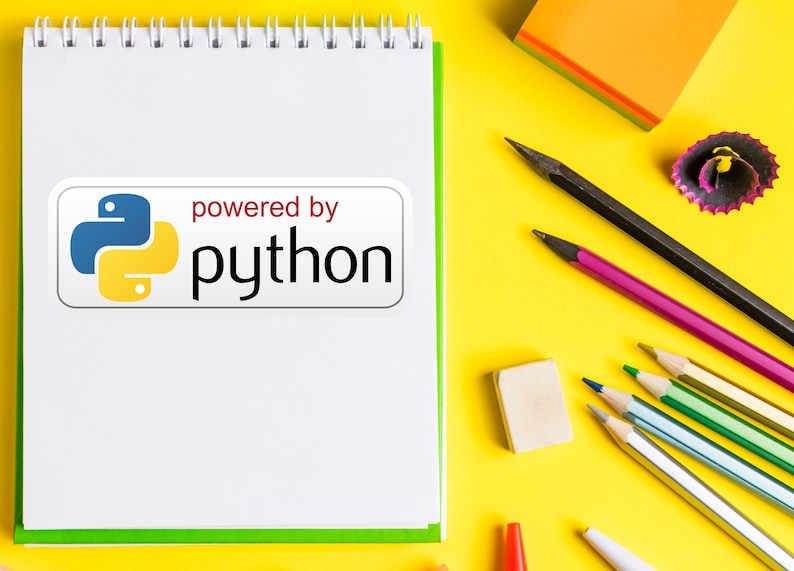 May include: A white spiral-bound notebook with a green border and the text "powered by python" on a white sticker. Pencils, an eraser, and a sharpener are scattered on a yellow surface.