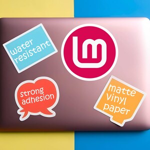 May include: A collection of stickers on a laptop. The stickers include a blue rectangle with "water resistant", a red circle with a white "lm" logo, an orange speech bubble with "strong adhesion", and an orange square with "matte Vinyl paper".