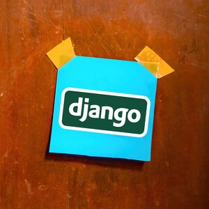 May include: A bright blue sticky note with the word "django" in white letters inside a green rectangle. The note is attached to a wooden surface with two pieces of yellow tape.
