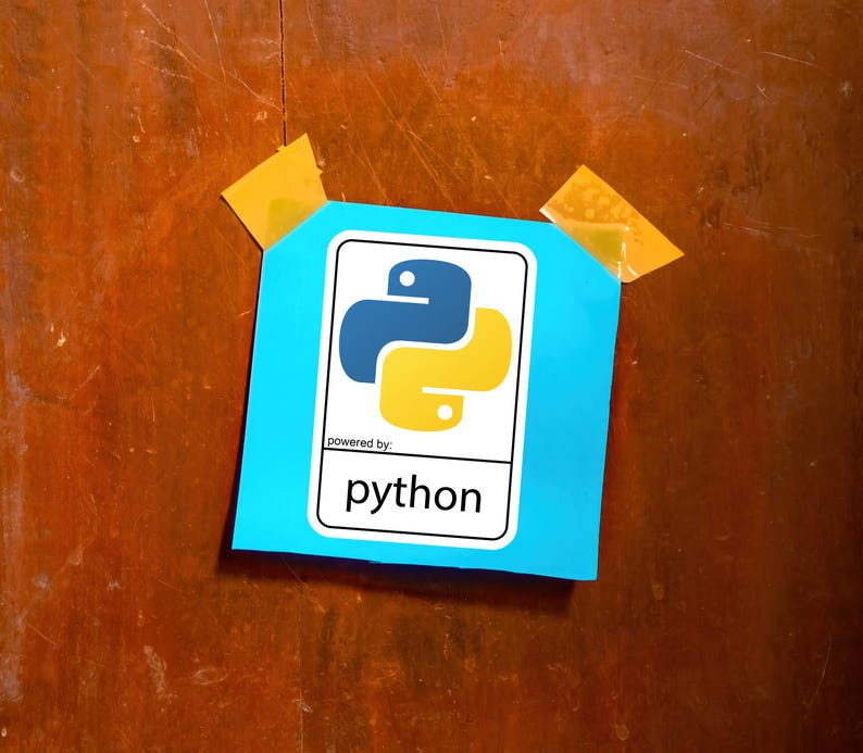 May include: A blue square with the Python logo, featuring a blue and yellow snake-like design, is taped to a wooden surface. The text "powered by: python" is below the logo. Two pieces of yellow tape secure the square.