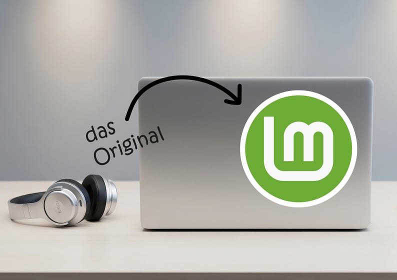 May include: A silver laptop with a green and white logo, and a pair of silver and black headphones. The laptop has a sticker with the Linux Mint logo. The text "das Original" is written above the laptop.