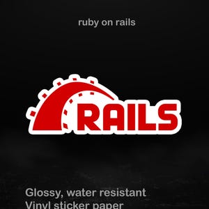 Könnte beinhalten: Ein rot-weißer Aufkleber mit dem Text "RAILS" in fetter Schrift. Der Aufkleber hat ein stilisiertes Design mit den Worten "ruby on rails" darüber. Der Aufkleber besteht aus glänzendem, wasserfestem Vinyl und ist in verschiedenen Größen erhältlich.