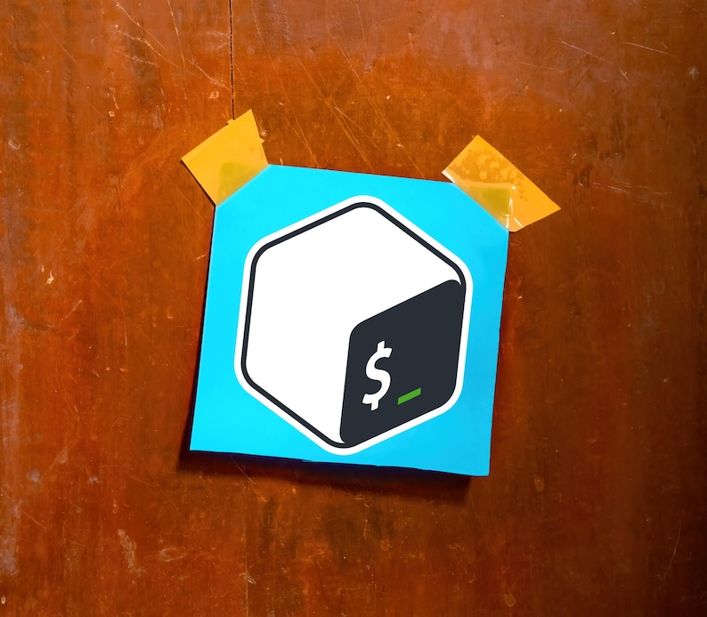 May include: A blue sticker with a white and black cube logo, featuring a dollar sign and a green underscore. The sticker is affixed to a wooden surface with two pieces of yellow tape.