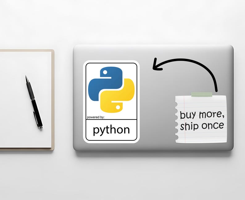 May include: A laptop with a Python sticker featuring a blue and yellow logo. A notepad with the text "buy more, ship once" is attached with tape. A pen and notepad are on the left.
