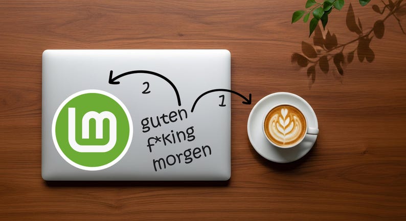 May include: A laptop with a green and white logo and the words "guten f*king morgen" is next to a cup of coffee with latte art on a wooden surface. A sprig of leaves is in the upper right corner.