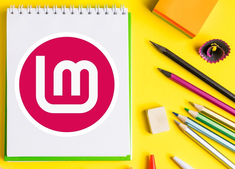 May include: A spiral-bound notepad with a white page featuring a magenta circle with a white "lm" logo. Pencils, an eraser, and a pencil sharpener are scattered on a bright yellow surface.