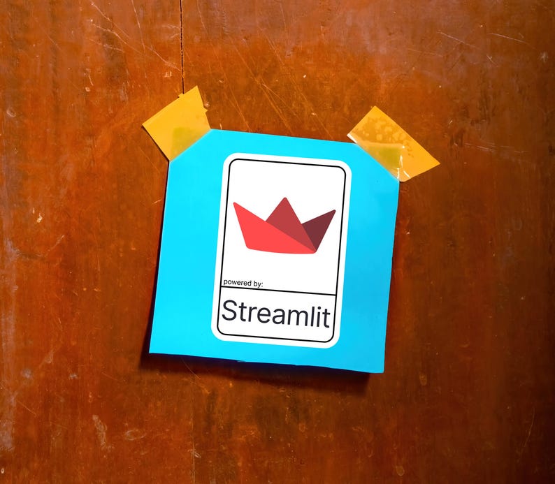 K&ouml;nnte beinhalten: Ein hellblaues Quadrat mit einem wei&szlig;en Rechteck, das ein rotes und kastanienbraunes Papierboot-Logo und den Text "powered by: Streamlit" enth&auml;lt. Das Quadrat ist mit gelbem Klebeband auf einer Holzoberfl&auml;che befestigt.