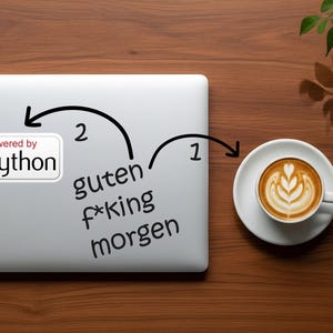 May include: A laptop with a "powered by python" sticker and the words "guten f*king morgen" written on it. A cup of coffee with latte art sits on a saucer to the right. The items are on a wooden surface.
