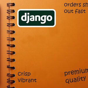 Może przedstawiać: Pomarańczowy notatnik w spiralę z czarnym długopisem i słowem "django" w białej czcionce w zielonym prostokącie. Notatnik zawiera r&oacute;wnież słowa "orders ship out fast", "Crisp Vibrant" i "premium quality".