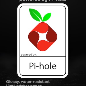 May include: A white rectangular sticker featuring a red and green graphic and the text "Pi-hole". The sticker also has the text "powered by Pi-hole" and "powered by:" in black. The sticker is made of glossy, water-resistant vinyl.