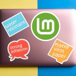 May include: A collection of stickers on a laptop. The stickers include a green circle with a white "Lm" logo, a blue rectangle with "water resistant", a red speech bubble with "strong adhesion", and an orange square with "matte Vinyl paper".