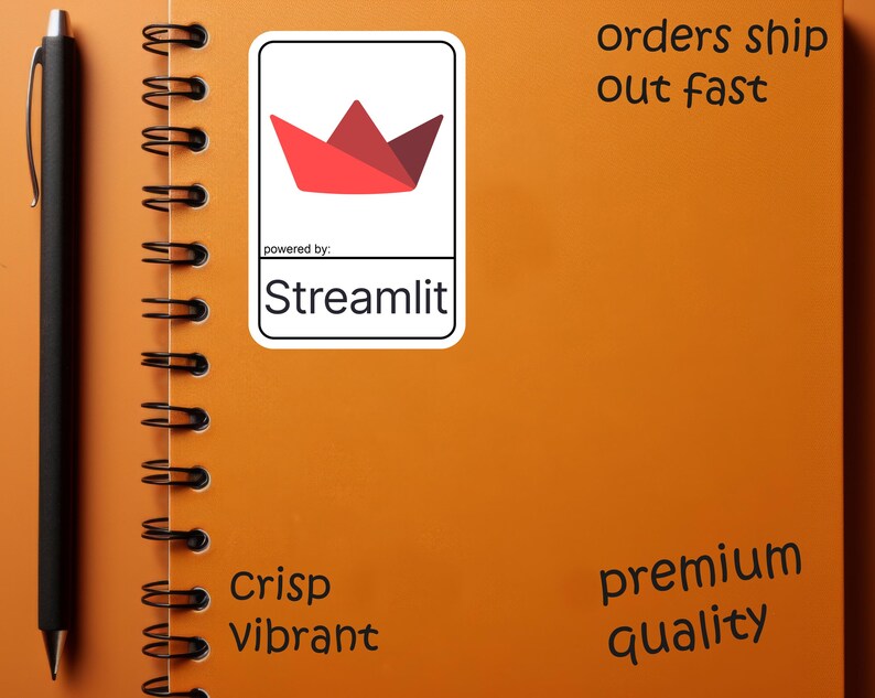 K&ouml;nnte beinhalten: Ein orangefarbenes Spiralnotizbuch mit einem schwarzen Stift und einem wei&szlig;en Aufkleber mit einem roten Papierboot-Design und dem Text "Streamlit". Das Notizbuch hat auch die W&ouml;rter "Crisp Vibrant" und "premium quality".
