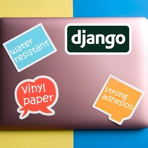 Może przedstawiać: Laptop z kilkoma naklejkami. Naklejki zawierają napisy "django", "water resistant", "vinyl paper" i "strong adhesion". Laptop znajduje się na ż&oacute;łto-niebieskim tle.