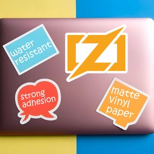 Puede incluir: Un conjunto de pegatinas sobre un ordenador port&aacute;til. Las pegatinas incluyen texto que dice "resistente al agua", "fuerte adhesi&oacute;n" y "papel vin&iacute;lico mate". Las pegatinas son de varias formas y colores, incluyendo azul, naranja y rojo.
