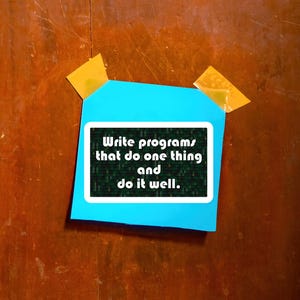 Pu&ograve; includere: Un post-it turchese con la scritta "Write programs that do one thing and do it well" in bianco. Il biglietto &egrave; attaccato a una superficie di legno con due pezzi di nastro adesivo giallo.